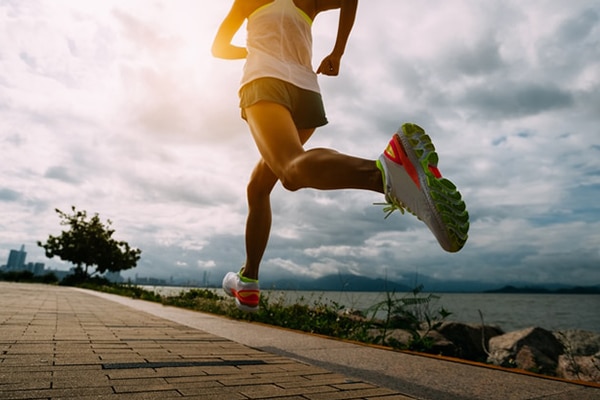 Fitness woman running training for marathon on sunny coast trail