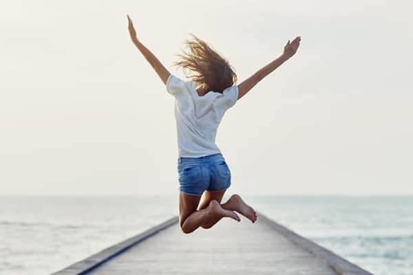 Back view of jumping girl on the pier