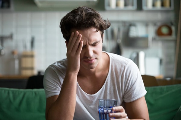 Young man suffering from headache, migraine or hangover at home